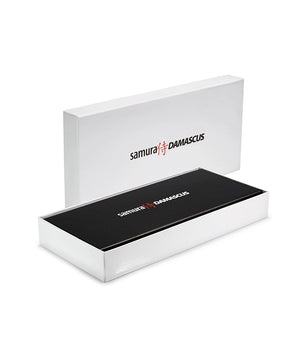 Eine weiße, rechteckige Schachtel mit leicht geöffnetem Deckel gibt den Blick auf ein schwarzes Innenleben frei. Das Samura-Logo in Schwarz und Rot ziert den Deckel und die Innenseite - ideal, um Ihr Samura DAMASKUS 3er-Messer Set - schwarz zu präsentieren.