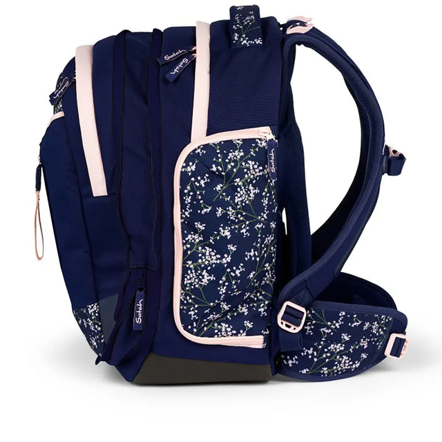 Der Satch Match Schulrucksack - Bloomy Breeze von Satch hat einen marineblauen Blumendruck, rosa Reißverschlüsse, Seitentaschen und gepolsterte Schultergurte - ein ergonomischer Schulrucksack, der Komfort und Stil vereint.